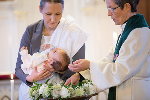 Pappi kastaa lasta. Kummi pitelee vauvaa.