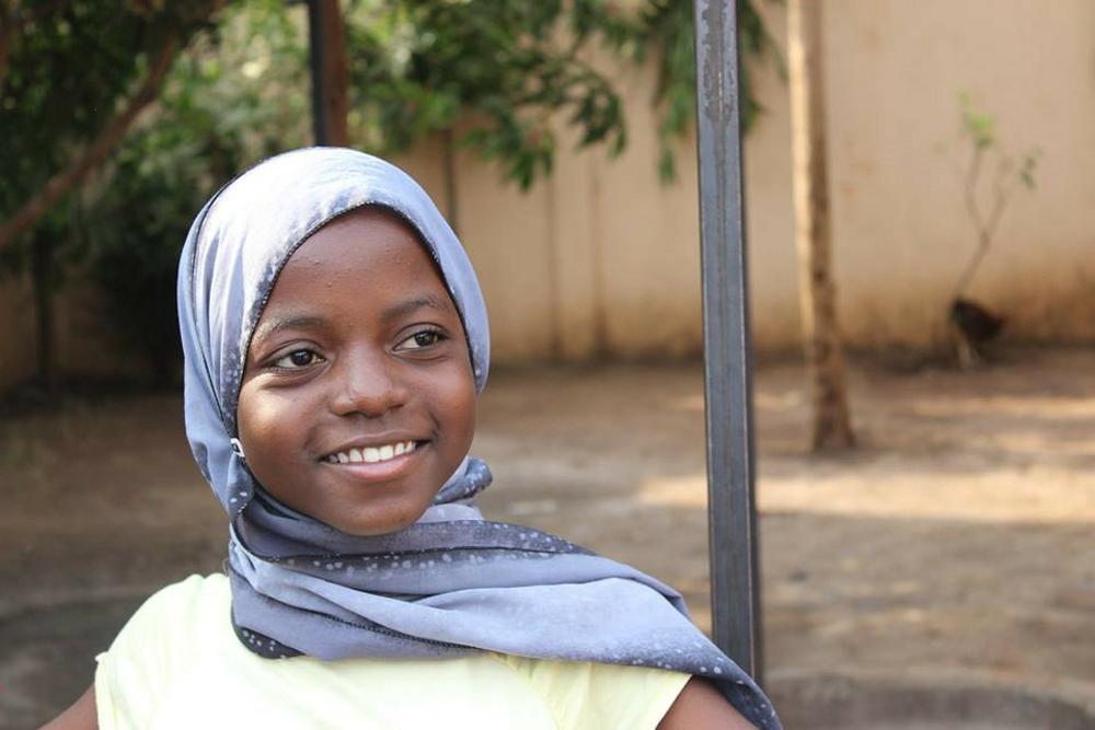 Tanzanialainen tyttö hymyilee kuvassa.