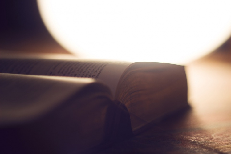 Pöydällä avoin Raamattu, takana kirkas valo